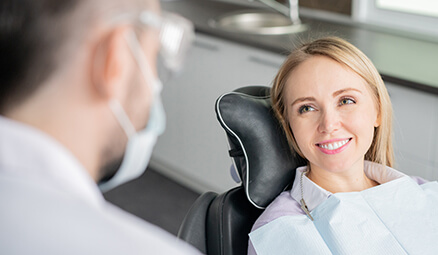 woman sitting in a dental chair, talking with her dentist