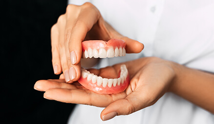 closeup of a person holding a set of full dentures