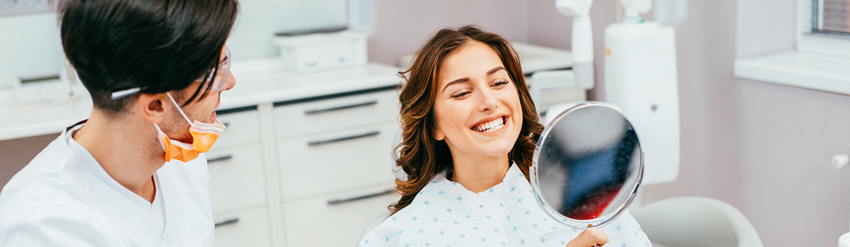 woman examining her smile in a mirror