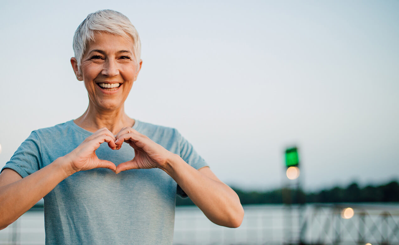 smiling woman making a heart sign with her hands