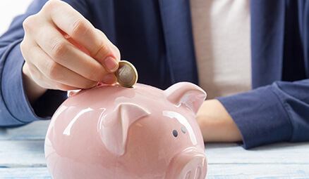 closeup of a person putting a coin into a piggy bank