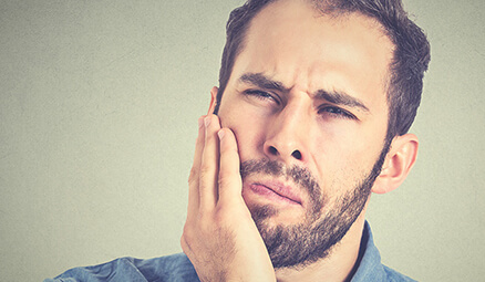 man holding his jaw in pain
