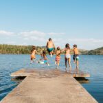 maintain healthy summer smile in the summer with swimming kids jumping off the dock