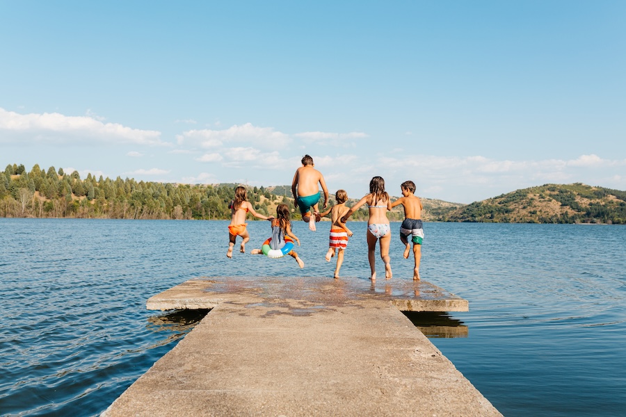 maintain healthy summer smile in the summer with swimming kids jumping off the dock