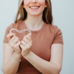 woman holding invisalign clear aligners in a heart shape to show the benefits of invisalign